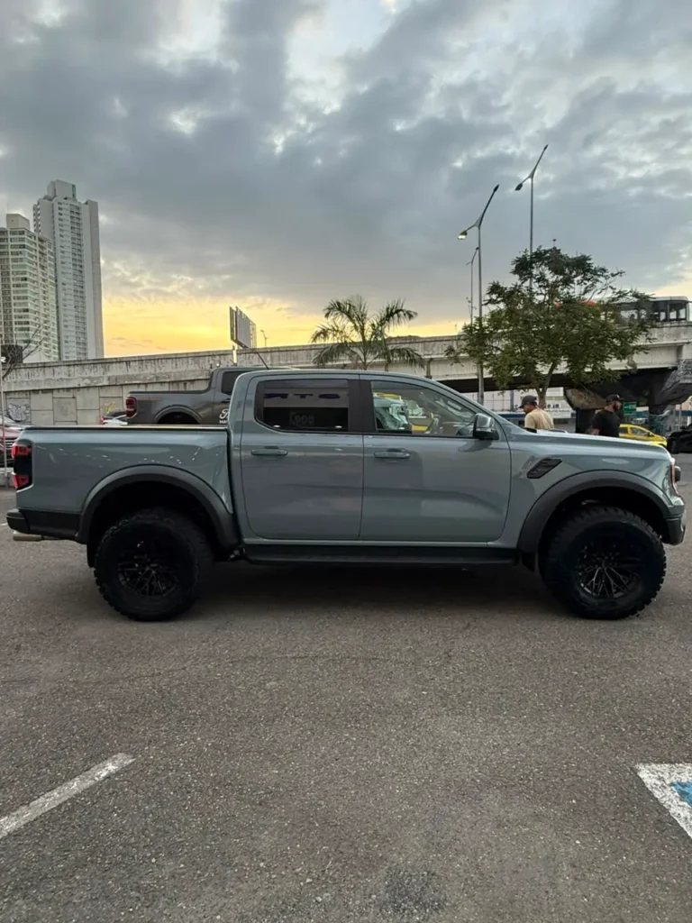 Camioneta pickup de color gris de doble cabina estacionada al aire libre con edificios de fondo.