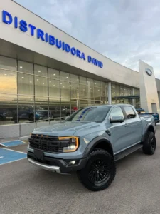Camioneta Ford Ranger Raptor gris estacionada frente al concesionario Distribuidora David con luces encendidas.