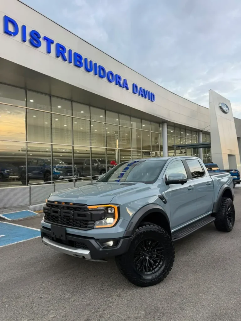Camioneta Ford Ranger Raptor gris estacionada frente al concesionario Distribuidora David con luces encendidas.
